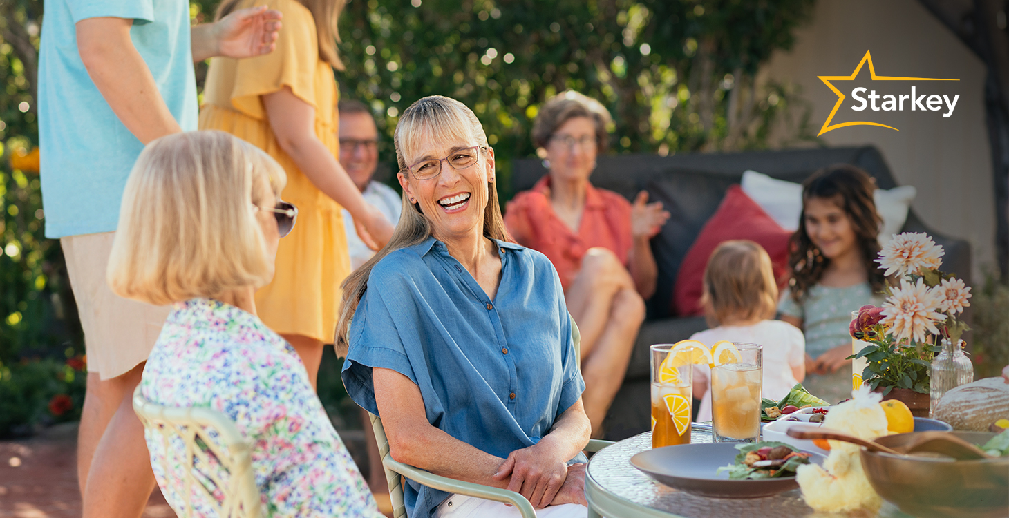 Middle aged woman laughing and enjoying an outdoor gathering with others